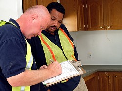 Inspectors stand before freshly installed cabinets in a FEMA trailer. Photo credit: Bicknell/FEMA.