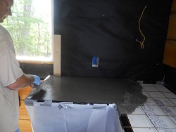 A concrete contractor spreads concrete on a countertop form.