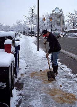 Photo of a man sprinkling sand on an icy sidewalk by Anna I/sxc.hu.