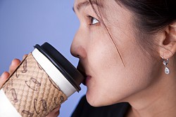 Photo of a woman drinking from a paper coffee cup by emyerson/istockphoto.com