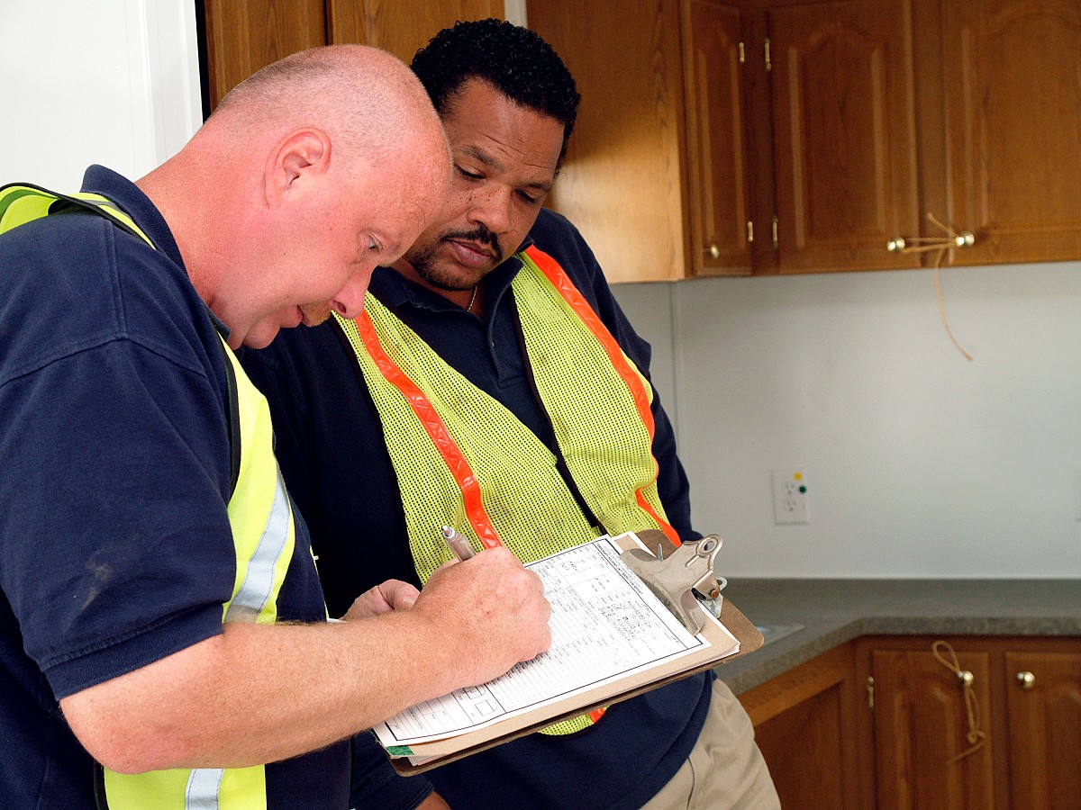 Inspectors stand before freshly installed cabinets in a FEMA trailer. Photo credit: Bicknell/FEMA.