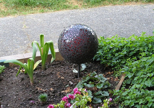 A DIY mosaic garden ornament gleams with pieces of broken mirror. (the1pony/flickr creative commons)