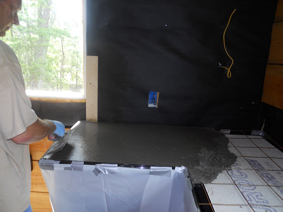 A concrete contractor spreads concrete on a countertop form.