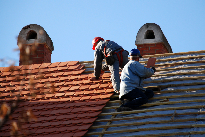Two roofers install clay roofing tiles, a green roofing material. (Photo: majorosl/istockphoto.com)