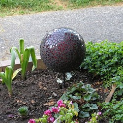 A DIY mosaic garden ornament gleams with pieces of broken mirror. (the1pony/flickr creative commons)